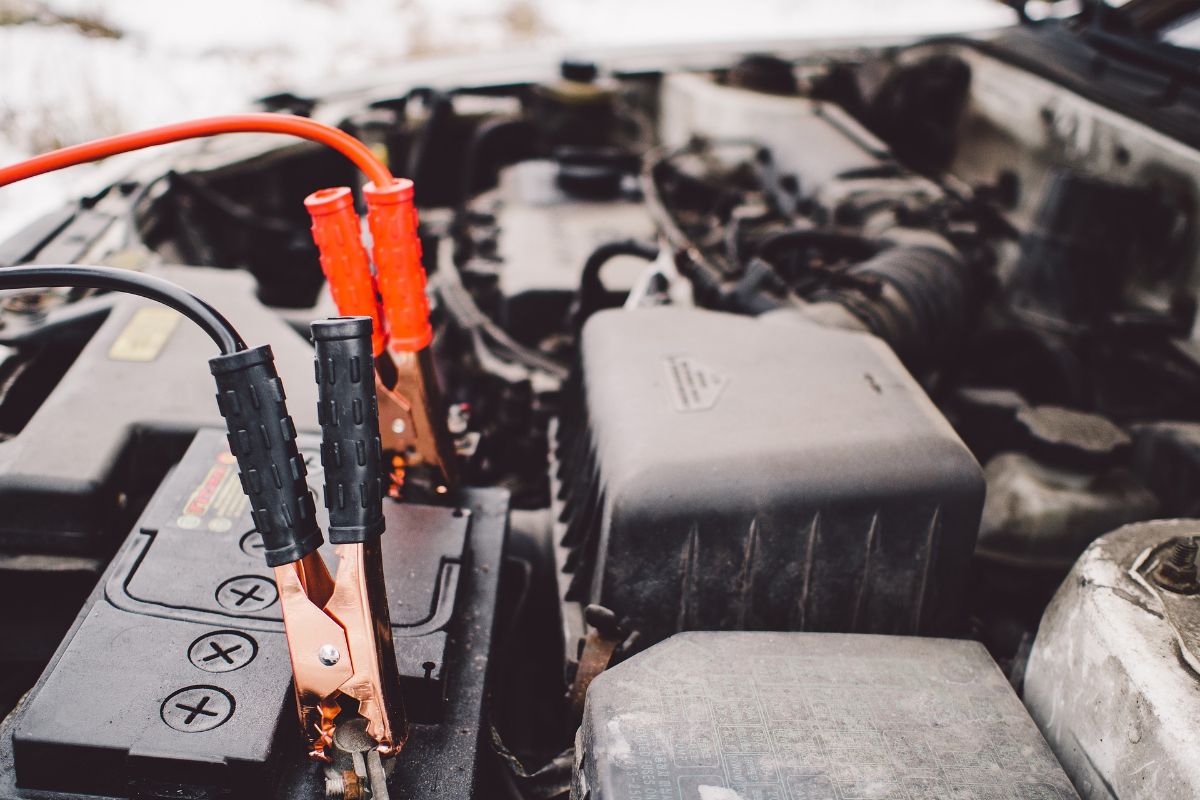 A close-up of cables connected to the car battery under the hood